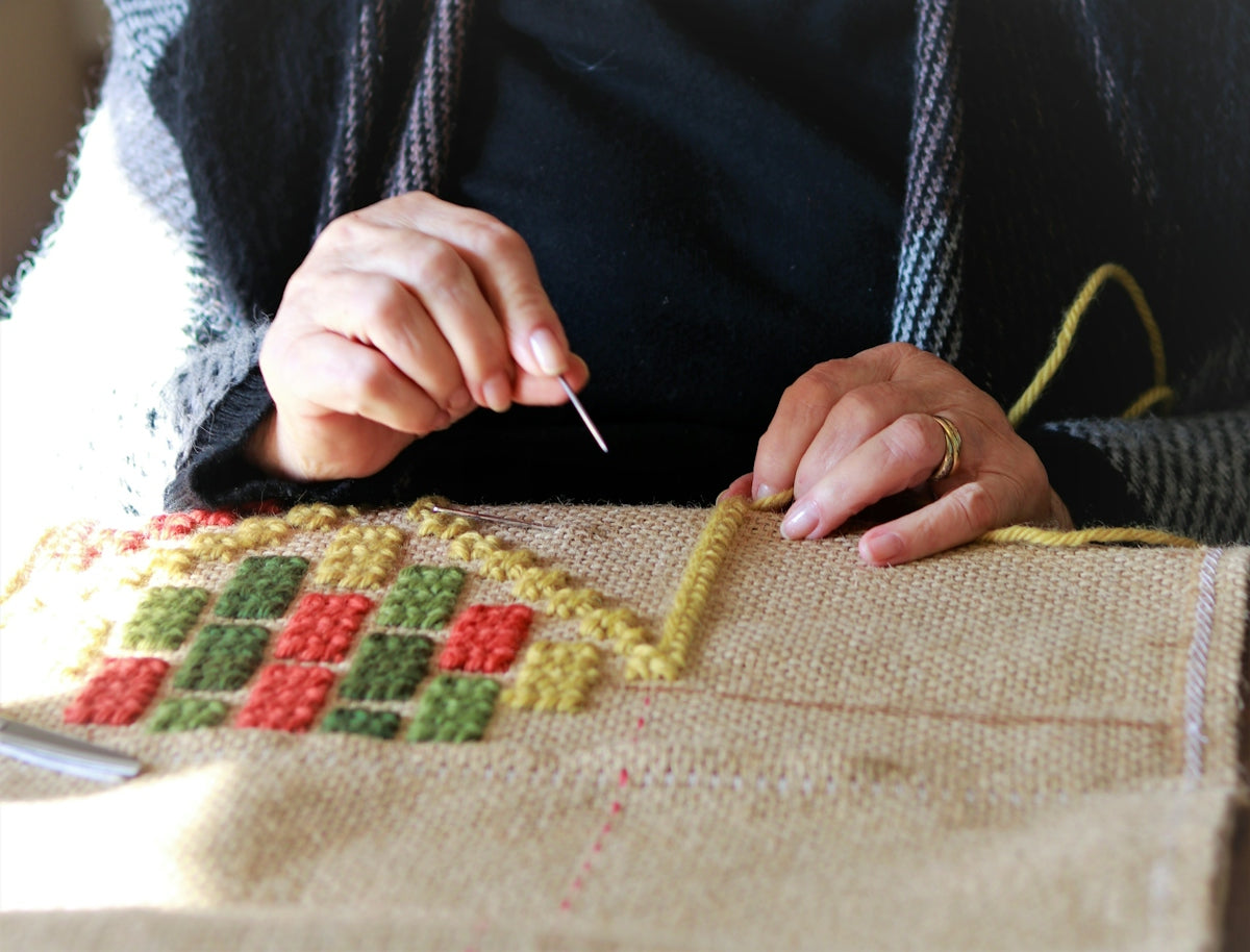 a woman is working on a cross stitch project